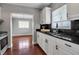 Kitchen featuring white cabinets, black granite countertops, stainless steel appliances, hardwood floors, and a window view at 417 20Th W Ave, Palmetto, FL 34221