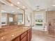 Bathroom showcasing a large vanity with granite counters, soaking tub, and glass shower at 431 Fieldstone Dr, Venice, FL 34292