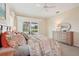 Bright main bedroom features a ceiling fan, patterned bedding, and dresser with a view of outdoor greenery at 431 Fieldstone Dr, Venice, FL 34292