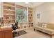 Bright home office with built-in bookshelves and a comfortable seating area at 4322 Reflections Pkwy, Sarasota, FL 34233
