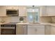 Bright kitchen featuring stainless steel appliances, white cabinetry, quartz countertops and modern lighting fixtures at 445 Matisse S Cir # 445, Nokomis, FL 34275
