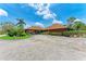 Home's exterior with covered carport, mature tropical landscaping and circular driveway at 4644 Red Maple Rd # 1303, Bradenton, FL 34210