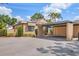 Tan home featuring a covered parking area and surrounding green landscaping at 5273 Myrtle Wood # 37, Sarasota, FL 34235