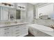 Luxurious bathroom with double vanity, modern lighting, and a soaking tub with marble tile surround at 5320 Layton Dr, Venice, FL 34293