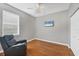 Cozy bedroom features hardwood floors, a ceiling fan, and a comfortable reclining chair near a window at 5320 Layton Dr, Venice, FL 34293