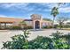 Community clubhouse with a landscaped parking area, palm trees and flowering shrubs at 5320 Layton Dr, Venice, FL 34293
