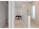 Hallway view of a beige-tiled shower with glass divider and pebble floor and a small decorative area with art at 5910 Red Mangrove Ln, Bradenton, FL 34210