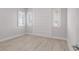 Empty bedroom with wood-look floors, paneled accent wall, and two large windows with shutters at 5910 Red Mangrove Ln, Bradenton, FL 34210