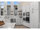 Bright kitchen featuring white cabinets, quartz countertops, stainless appliances, floating shelves, and tile backsplash at 5910 Red Mangrove Ln, Bradenton, FL 34210