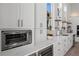 Bright kitchen featuring white cabinets, quartz countertops, stainless steel appliances, and floating wood shelves at 5910 Red Mangrove Ln, Bradenton, FL 34210