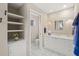 Bathroom featuring a white vanity with storage, decorative mirror, sconce lighting, shelving and tiled flooring at 6664 Deering Cir, Sarasota, FL 34240