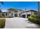 Stately home featuring a barrel tile roof, lush tropical landscaping, and a paver driveway leading to a two-car garage at 6919 Westchester Cir, Lakewood Ranch, FL 34202