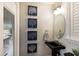 A stylish powder room features an oval mirror, black pedestal sink, and custom artwork at 6919 Westchester Cir, Lakewood Ranch, FL 34202