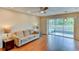 Cozy living room featuring hardwood floors and a glass sliding door that opens to the backyard and pool at 7719 9Th Avenue Nw Dr, Bradenton, FL 34209