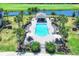 Aerial view of a luxurious pool area featuring a well-appointed clubhouse, lounge chairs, and palm trees at 18113 Gawthrop Drive # 101, Lakewood Ranch, FL 34211