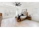 Bright bedroom with wood-look tile flooring, tray ceiling, large windows, and a ceiling fan at 18215 Cayo Largo Pl, Bradenton, FL 34202