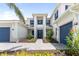 Beautiful two-story home featuring a stylish entrance, blue shutters, lush landscaping, and a two-car garage at 18215 Cayo Largo Pl, Bradenton, FL 34202