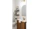 Chic powder room with wood vanity, gold fixtures, arched mirror, and decorative shelving at 18215 Cayo Largo Pl, Bradenton, FL 34202