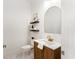 Stylish powder room with wood vanity, gold fixtures, arched mirror, and decorative shelving at 18215 Cayo Largo Pl, Bradenton, FL 34202