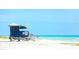 Scenic view of a blue lifeguard station on a white sand beach with colorful umbrellas and ocean waves at 2141 Cork Oak St, Sarasota, FL 34232