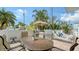 A spacious patio with outdoor seating, lounging chairs, and shade from palm trees is perfect for relaxation at 220 36Th St, Holmes Beach, FL 34217