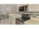 Kitchen counter and view of dining room and appliances, including microwave and cooktop at 2759 Starview Ave, North Port, FL 34288