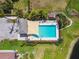 Bird's eye view of a community pool with palm trees, sun shade, lounge seating, landscaping and other neighborhood homes at 327 64Th Avenue E Cir, Bradenton, FL 34203