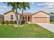 Charming single-story home with a well-kept lawn, palm trees, and an attached garage at 327 64Th Avenue E Cir, Bradenton, FL 34203