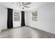 Bright bedroom featuring light-colored floors, dark curtains, a ceiling fan, and two large windows at 3616 Stardust Pl, Sarasota, FL 34232