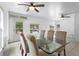 Bright dining room area with a glass table and tan upholstered chairs sits near three windows and door at 3616 Stardust Pl, Sarasota, FL 34232