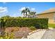 Serene backyard featuring a tall hedge, white rock ground cover, and glimpses of a screened enclosure at 370 Londonderry Dr, Sarasota, FL 34240