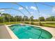 Large screened-in pool with views of a lush green lawn and mature trees beyond at 370 Londonderry Dr, Sarasota, FL 34240