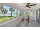 Light-filled sunroom with scenic lake views through expansive windows and ceiling fan, features unique driftwood art piece at 415 Courbet Dr # 415, Nokomis, FL 34275