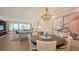Bright dining room with a round table, white chairs, modern chandelier, and ocean view at 435 L Ambiance Dr # K506, Longboat Key, FL 34228