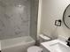 Bathroom featuring marble style tiling, a bathtub and shower combination, and modern fixtures at 4613 Muirfield Dr, Bradenton, FL 34210