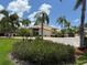Community clubhouse surrounded by lush landscaping, palm trees, and vibrant floral arrangements at 4613 Muirfield Dr, Bradenton, FL 34210