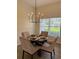 Cozy dining area featuring modern chandelier, a dark wood table, and natural light from the adjacent window at 4613 Muirfield Dr, Bradenton, FL 34210