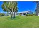 Beautiful home exterior with a lush green lawn, mature palm trees, and serene waterfront views at 4726 Potomac Cir, Bradenton, FL 34210