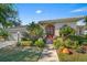 Beautifully landscaped front yard with mature trees, shrubs, and a charming walkway leading to the entrance at 4978 Cedar Oak Way, Sarasota, FL 34233