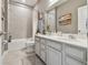 Bright bathroom featuring double sinks, gray cabinets, framed mirror, tub and shower combination and gray tile at 5904 114Th E Dr, Parrish, FL 34219