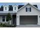 Charming home exterior featuring light siding, a dark roof, dormer windows, and an attached two-car garage at 650 Maldives Trl, Sarasota, FL 34234
