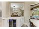 Stylish bar area with a built-in wine refrigerator, counter seating, and a view of the dining and pool areas at 6674 Coopers Hawk Ct, Lakewood Ranch, FL 34202