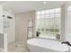 Modern bathroom with a freestanding tub, glass block window, and a stylish shower with sleek fixtures at 6674 Coopers Hawk Ct, Lakewood Ranch, FL 34202