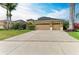 Spacious house exterior featuring a large driveway, three-car garage, mature landscaping, and a well-manicured lawn at 6674 Coopers Hawk Ct, Lakewood Ranch, FL 34202