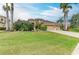 A spacious home featuring manicured lawns, lush landscaping, palm trees, and a large driveway leading to a three-car garage at 6674 Coopers Hawk Ct, Lakewood Ranch, FL 34202