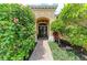 Charming home entrance with a brick walkway, lush landscaping, a covered porch, and decorative double doors at 6674 Coopers Hawk Ct, Lakewood Ranch, FL 34202