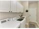 Bright laundry room features white cabinetry, tile backsplash, washer and dryer with sink at 6674 Coopers Hawk Ct, Lakewood Ranch, FL 34202