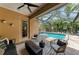 Comfortable covered patio with ceiling fan, wicker furniture, fire pit, and view of the pool at 6674 Coopers Hawk Ct, Lakewood Ranch, FL 34202