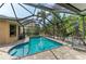 The inviting pool area features clear water, brick patio, privacy screening, and lush tropical landscaping at 6674 Coopers Hawk Ct, Lakewood Ranch, FL 34202