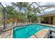 Screened pool with brick pavers, lush landscaping, and covered outdoor seating and kitchen area at 6674 Coopers Hawk Ct, Lakewood Ranch, FL 34202